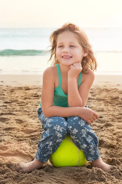 Meisje zittend op een bal op strand — Stockfoto