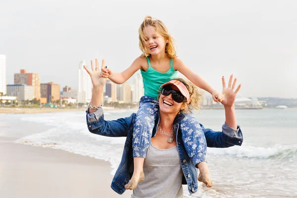 girl sitting on mother\'s shoulders