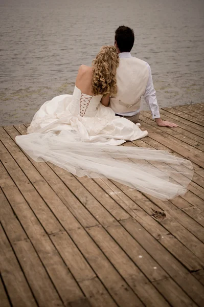 Mariée et marié se détendre sur un quai en bois — Photo