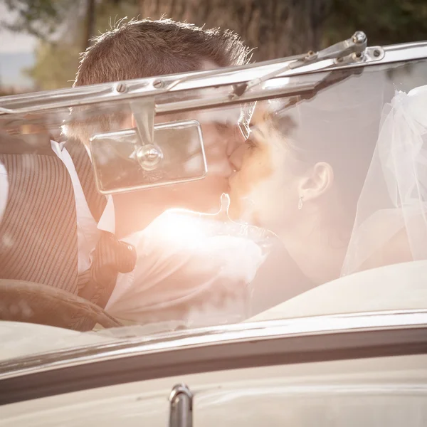 Couple nouvellement marié embrasser dans une voiture vintage — Photo