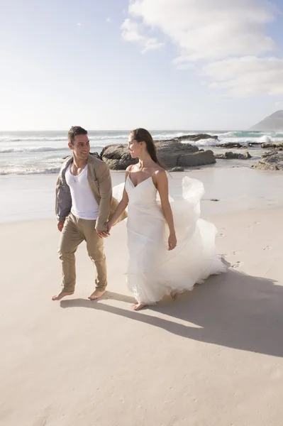 Mariée et marié marchant au bord de la mer — Photo