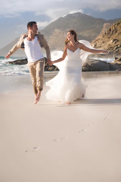 Novia y novio corriendo a la orilla del mar —  Fotos de Stock