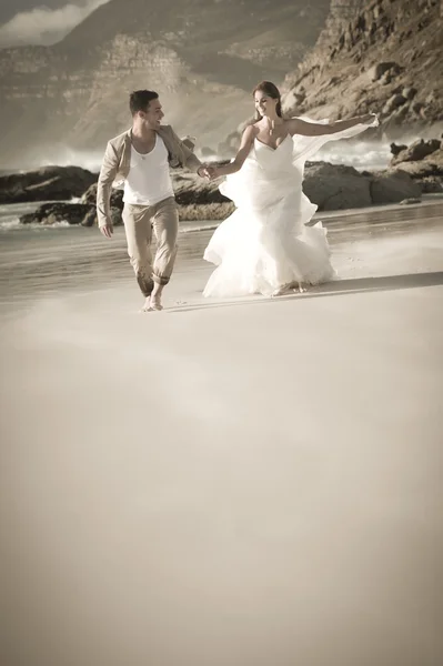 Menyasszony és a vőlegény a tengerparton fut — Stock Fotó
