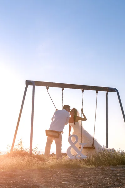 Casal recém-casado beijando em balanços — Fotografia de Stock