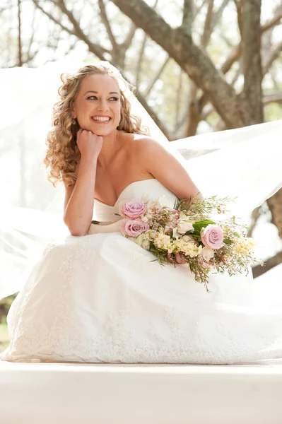 Braut sitzt und hält Blumenstrauß — Stockfoto