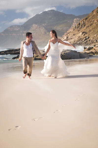 Mariée et marié courant au bord de la mer — Photo