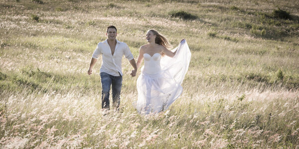 Bride and groom walking in field, wedding concept