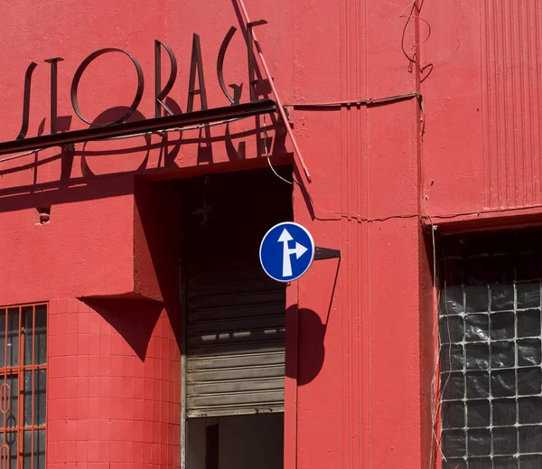 Rotes Gebäude und blaues Verkehrsschild Stockfoto