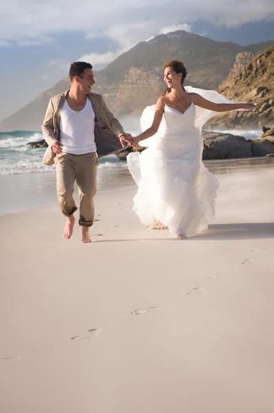 Mariée et marié courant au bord de la mer — Photo