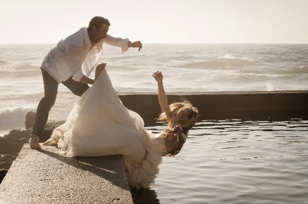 Groom pushing bride in water — Stock Photo, Image