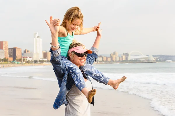 girl sitting on mother\'s shoulders