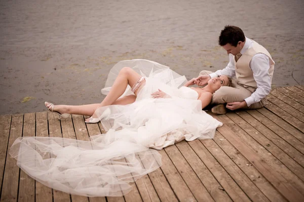 Bruid en bruidegom ontspannen op houten dok — Stockfoto