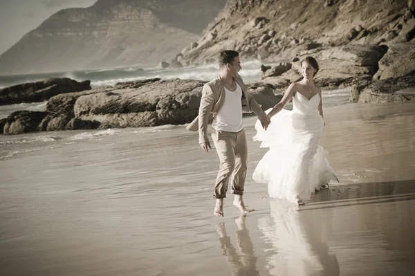 Braut und Bräutigam spazieren am Meer — Stockfoto