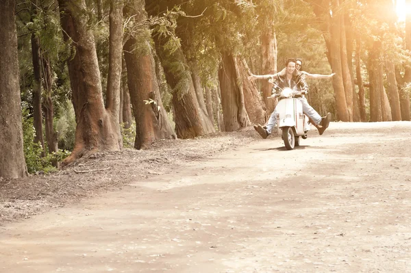 Young happy couple traveling by scooter along dirt road — Stock Photo, Image