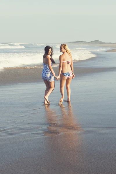 Dos chicas jóvenes atractivas en la playa en bikini divirtiéndose —  Fotos de Stock