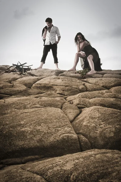 Beautiful couple flirting and having fun together on beach rocks — Stock Photo, Image