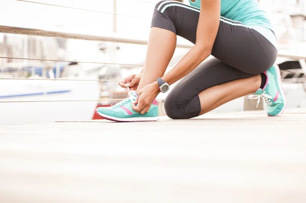 Close up of runner tying shoe laces on wooden boardwalk — Stock Photo, Image