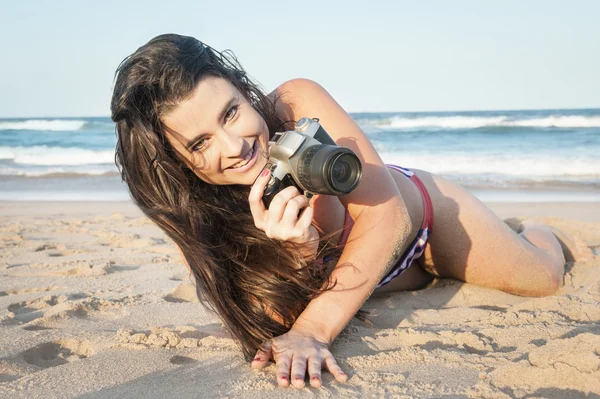 Jovem menina atraente tirar fotos com câmera na praia — Fotografia de Stock