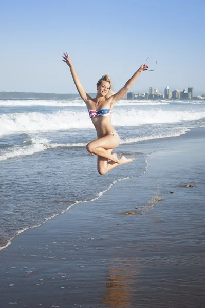 Joven chica rubia atractiva saltando en la playa en bikini —  Fotos de Stock