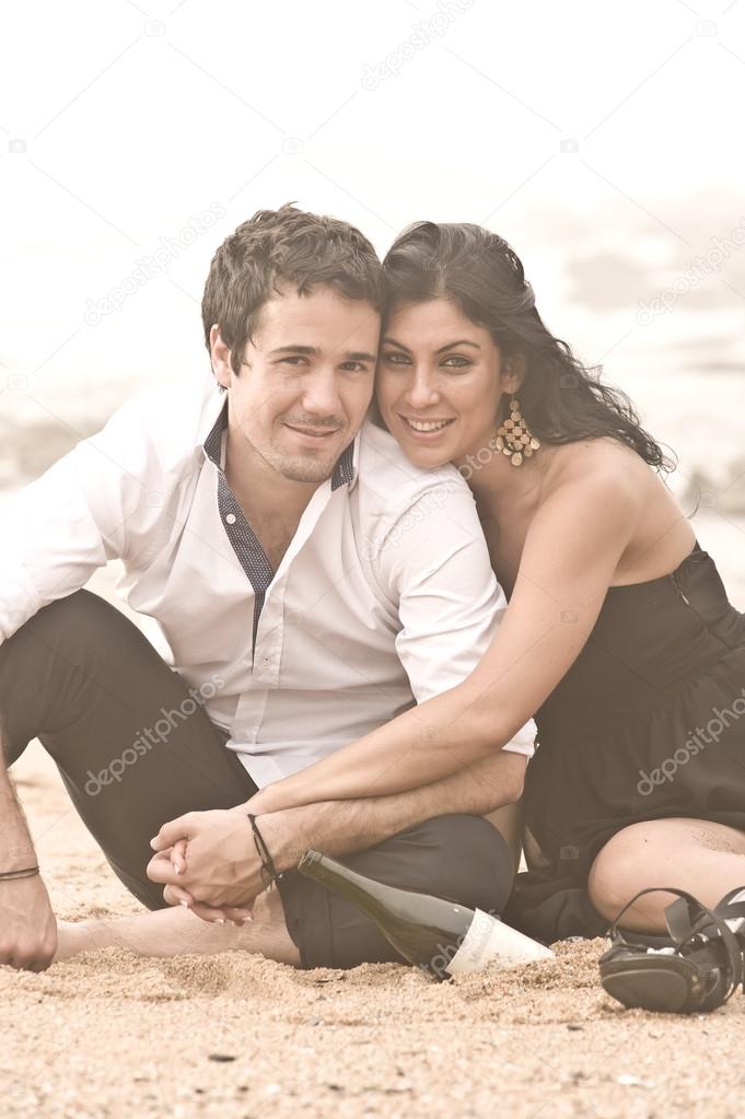 Happy attractive couple flirting on beach rocks under cloudy skies