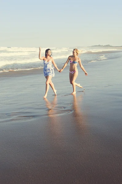 Duas meninas lésbicas atraentes jovens andando ao longo da praia de mãos dadas — Fotografia de Stock