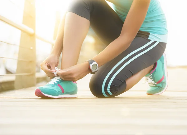 Close up of runner tying shoe laces on wooden boardwalk — Stock Photo, Image