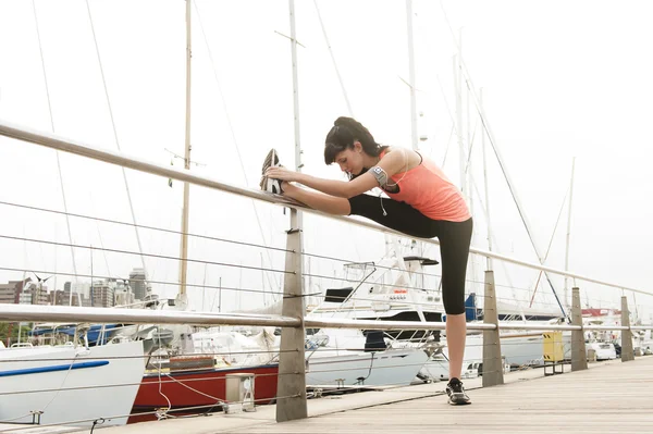 Joven mujer atractiva estirando sus piernas antes de una carrera matutina — Foto de Stock