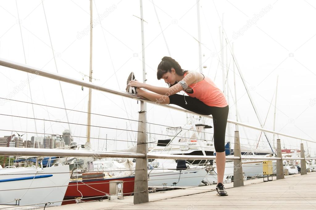 Young attractive woman stretching her legs before a morning run