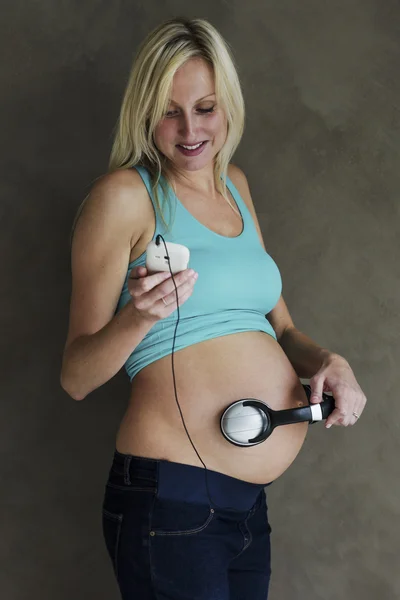 Mujer embarazada joven bailando música con su hijo nonato — Foto de Stock
