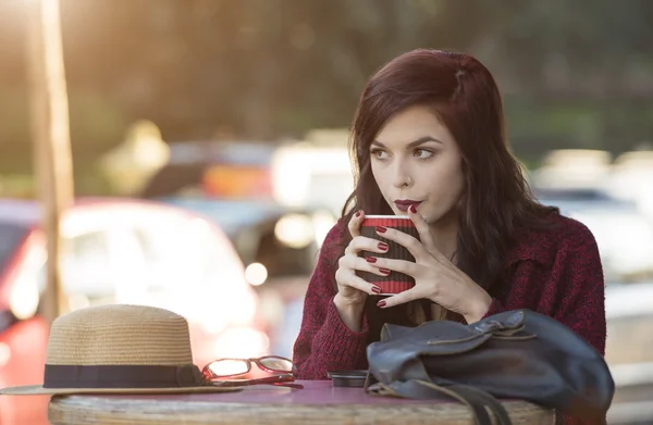 Jeune femme dégustant une boisson dans un café extérieur — Photo