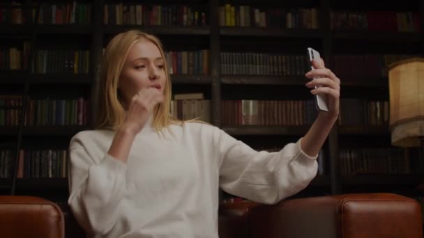 Joven rubia caucásica mujer inspiradora charlando con amigos usando vídeo en un teléfono — Vídeos de Stock