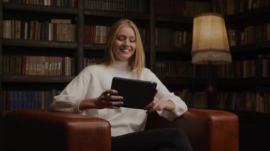 Genç, beyaz, sarışın bir kadın arkadaşlarıyla tablet kullanıyor.