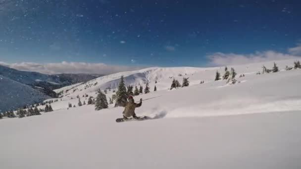 Schneespray in der Kamera, während ein Snowboarder an einem frostigen sonnigen Tag in den Bergen seine Runden dreht — Stockvideo