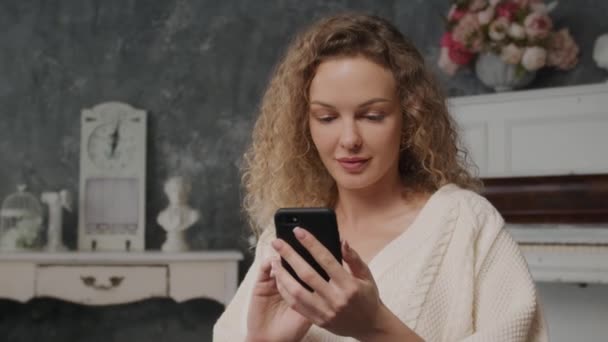 En 30-tals person ung kaukasiska blond kvinna blyg sms:a på sin telefon och ler sensuellt — Stockvideo