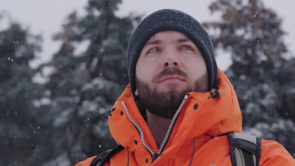 Крупным планом или портретом молодого кавказца, смотрящего вдаль и согревающего руки в снежный зимний день — стоковое видео
