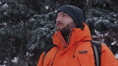 30 'lu yaşlardaki neşeli beyaz adam dışarıda karlı bir kış günü etrafa bakıp gülümsüyor.