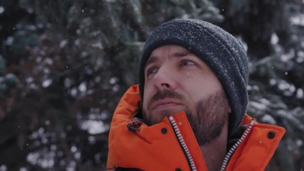 Молодой парень смотрит где-то в морозный и снежный зимний день крупным планом — стоковое видео
