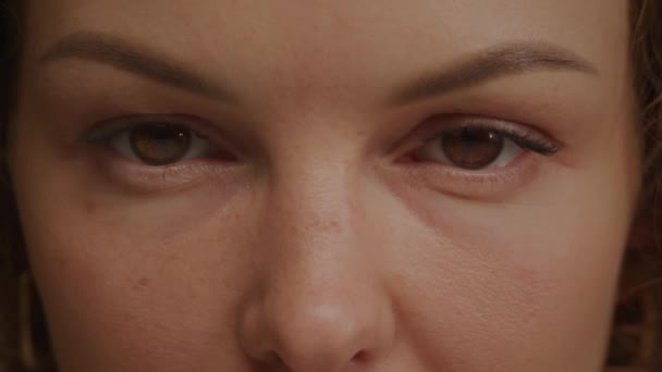 Extremo close-up de uma mulher caucasiana dos anos 30 com olhos castanhos abrindo e olhando para a câmera — Vídeo de Stock