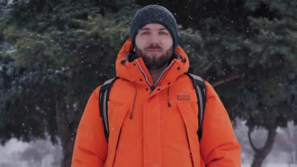 Портрет бородатого человека, стоящего возле сосен в снежный зимний день — стоковое видео