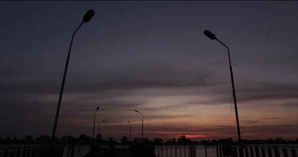 Senja di atas sungai dengan tiang lampu dalam silhuette Stok Foto