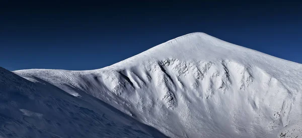 Pico isolado da montanha coberto de neve com céu azul claro Imagem De Stock