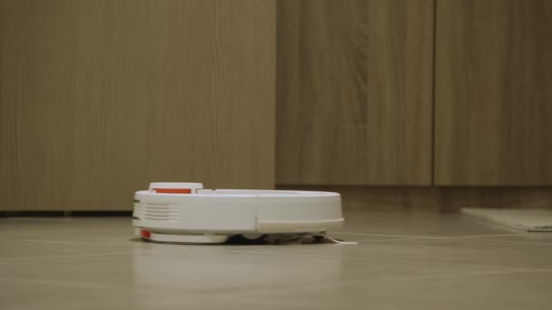 Un robot de trapeador de vacío blanco limpiando un piso de madera en un interior de apartamento brillante — Vídeos de Stock