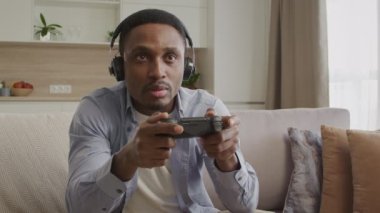 Genç, Afro-Amerikan bir adam arkadaşlarıyla çevrimiçi bir konsolda oynarken aynı zamanda kulaklık kullanarak onlarla sohbet ediyor.