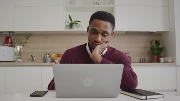 Bored african american man stuck in front of a laptop computer at home office — Stock Video