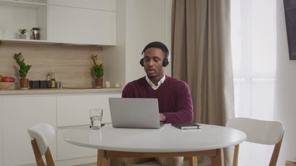 一个戴耳机工作在笔记本电脑上的年轻非洲裔美国人的全景照片。在呼叫中心的近旁工作的人 — 图库视频影像