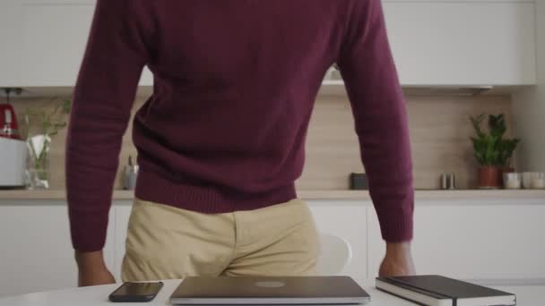 Een Afro-Amerikaanse twintiger loopt in het frame, opent de laptop en gaat aan het werk. — Stockvideo