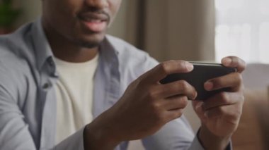Afro-amerikan tanınmayan erkek ellerini akıllı bir telefonla çevrimiçi oyun oynarken yaklaş.