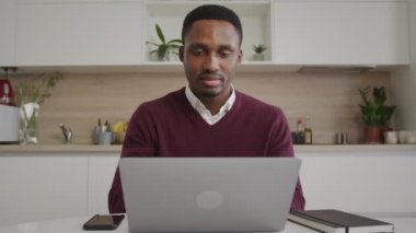 Afrikalı Amerikalı yetişkin adam evden uzak bir dizüstü bilgisayarda başarılı bir şekilde çalışıyor.