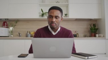Afro-Amerikalı genç siyahi girişimci bilgisayarında çalışırken mutlu ve gülümsüyor.