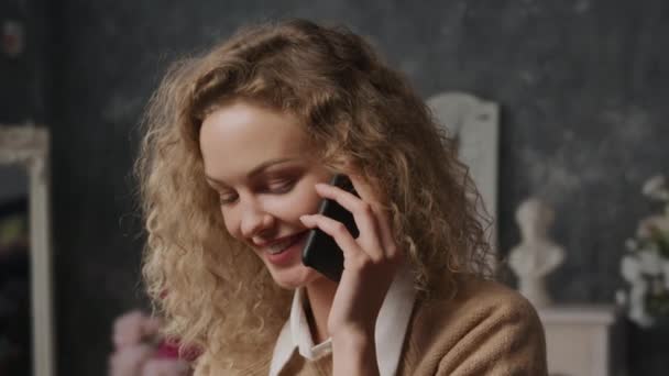 Primo piano di una giovane donna caucasica timida che parla al telefono al chiuso — Video Stock